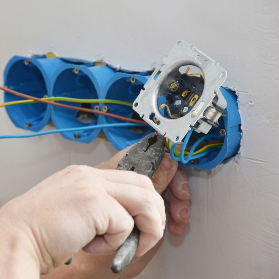 Elektricien sluit een nieuw stopcontact aan op de bedrading in de inbouwdoos